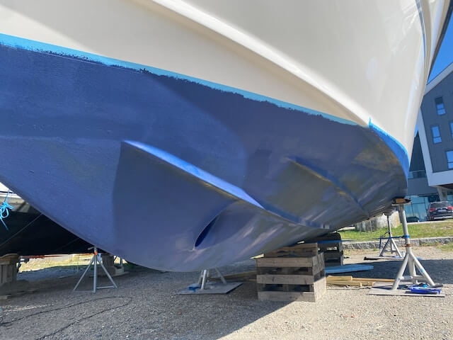 White boat on dry dock with fresh blue antifouling paint drying